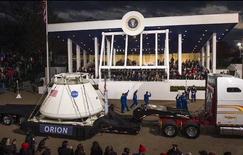 Une réplique d'Orion passe devant la tribune présidentielle, accompagnée d'astronautes américains saluant le président Obama